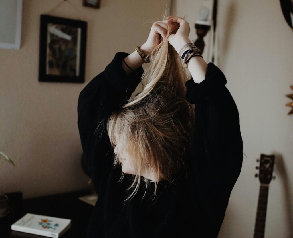 Femme en pull noir tenant ses cheveux