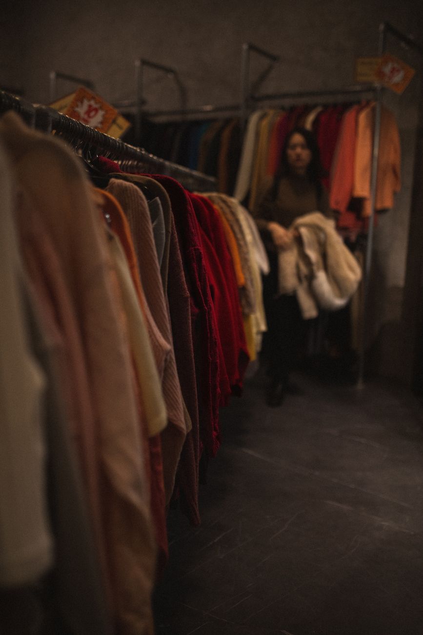 Magasin de vêtements faiblement éclairé avec une femme faisant du shopping à Milan, en Italie.